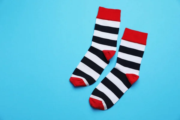 Striped socks on light blue background, flat lay. Space for text