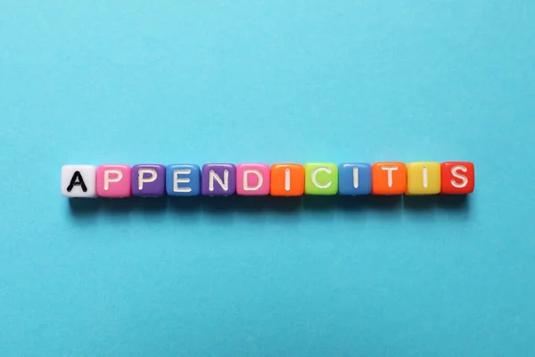 Word Appendicitis made of color cubes with letters on light blue background, top view