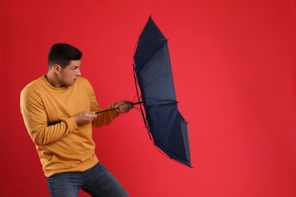 Şemsiyeli Duygusal Adam Kırmızı Arka Planda Rüzgarın Esintisine Yakalandı — Stok fotoğraf