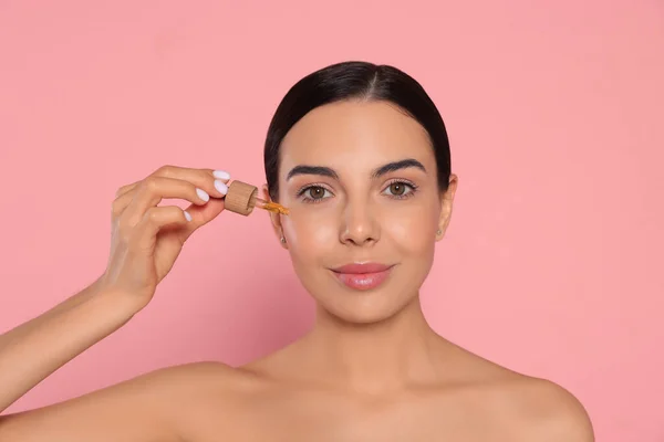 Giovane Donna Che Applica Olio Essenziale Sul Viso Sullo Sfondo — Foto Stock