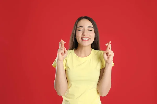 Excited Young Woman Holding Fingers Crossed Red Background Superstition Good — Stock Photo, Image
