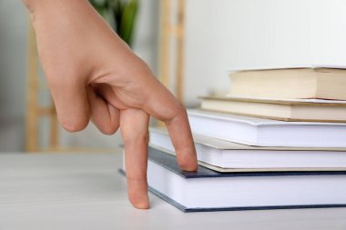 Woman imitating stepping up on books with her fingers indoors, closeup