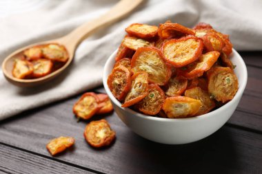 Kahverengi ahşap masada kurutulmuş kumkatlı kase ve kaşık.