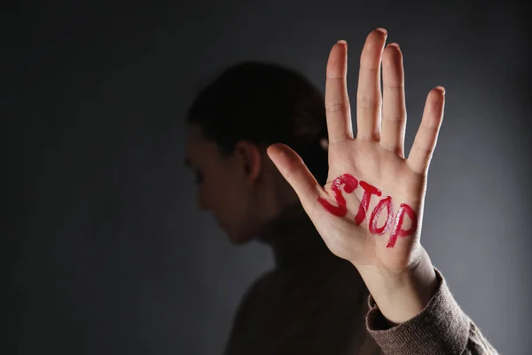 Woman with word Stop written on hand against black background, closeup and space for text. Domestic violence concept