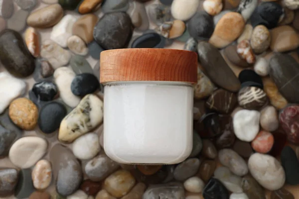 Jar of cosmetic product on wet stones, top view