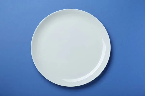 蓝色背景的空白色陶瓷盘 顶部视图 — 图库照片