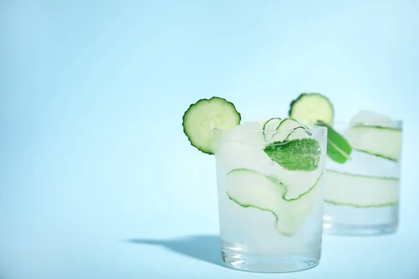 Tasty fresh cucumber water with mint on light blue background, space for text
