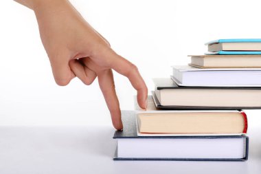 Woman imitating stepping up on books with her fingers against white background, closeup