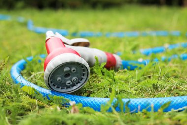 Watering hose with sprinkler on green grass outdoors, closeup