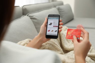 Kredi kartı olan bir kadın kapalı mekanlarda alışveriş yapmak için akıllı telefon kullanıyor.