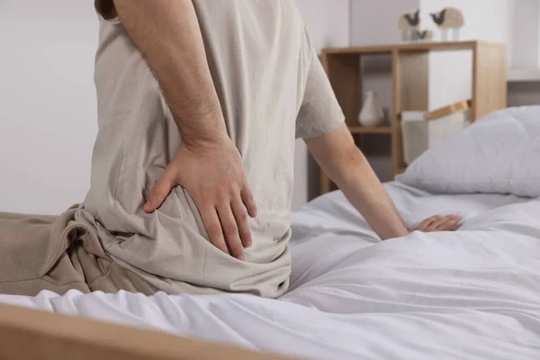 部屋のベッドに座っている間 背中の痛みに苦しむ男 クローズアップ 大腸炎の症状 — ストック写真