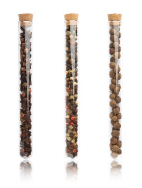 Beyaz zemin üzerinde farklı baharatlar bulunan cam tüpler.