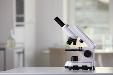Laboratuvarda beyaz masa üzerinde modern tıbbi mikroskop, metin için alan