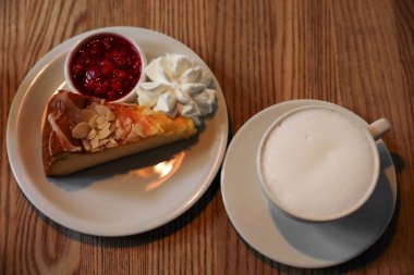Bir fincan aromatik kahve ve ahşap masada lezzetli bir tatlı.