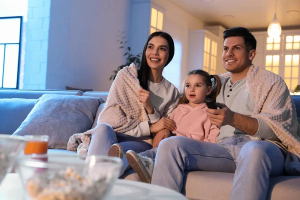 Family watching movie on sofa at night