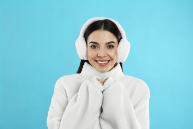 Açık mavi arka planda kulaklık takan güzel bir genç kadın.