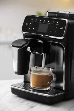 Modern espresso makinesi ve mutfakta beyaz mermer tezgahta sütlü cam kahve.