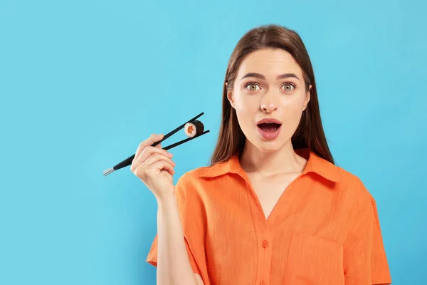 Emotionale Junge Frau Hält Sushi Rolle Mit Essstäbchen Auf Hellblauem — Stockfoto