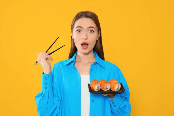 Känslomässig Ung Kvinna Med Platta Sushi Rullar Och Ätpinnar Orange — Stockfoto