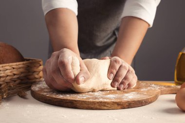 Gri duvarın yanındaki masada hamur yoğuran adam, yakın plan.
