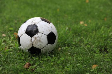 Açık havada yeşil çimlerde kirli futbol topu, metin için alan