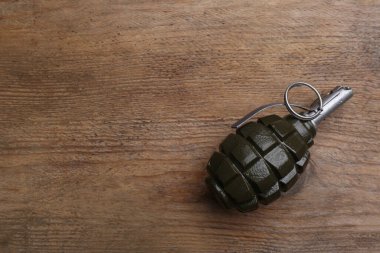 Hand grenade on wooden table, top view. Space for text