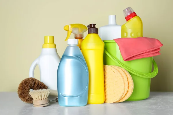Different cleaning supplies and tools on table against beige