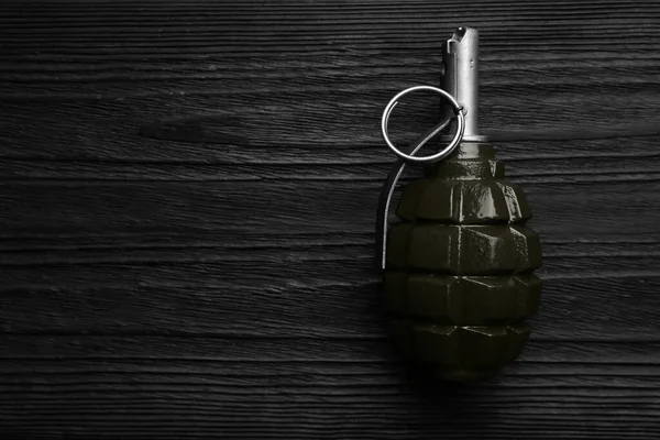 Hand grenade on black wooden table, top view. Space for text