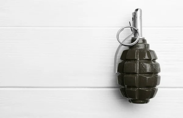 Hand grenade on white wooden table, top view. Space for text