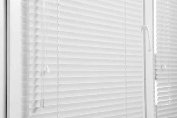 Window with closed white horizontal blinds indoors, closeup