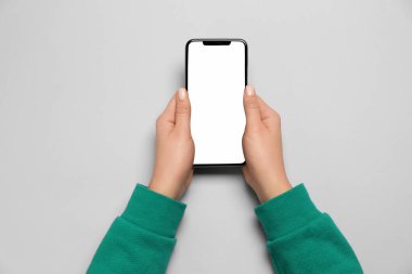 Açık gri arka planda akıllı telefonu olan kadın, üst görünümde.