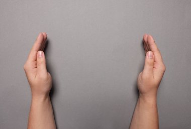 Gri arka planda tutulan bir kadın, yakın plan elleri. Metin için boşluk