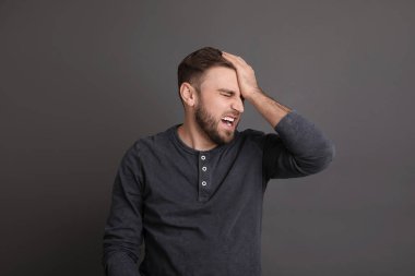 Portrait of emotional young man on grey background. Personality concept