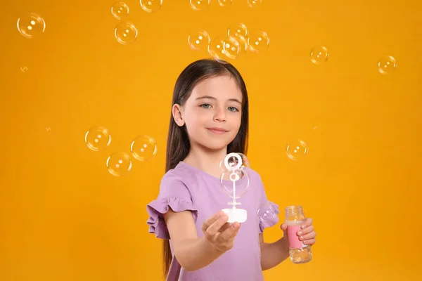 Niña Divirtiéndose Con Burbujas Jabón Sobre Fondo Amarillo — Foto de Stock