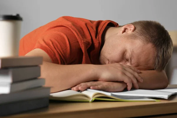 Moe Man Slapen Buurt Van Boeken Aan Houten Tafel Binnen — Stockfoto