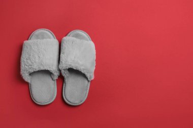 Kırmızı arka planda bir çift yumuşak pofuduk terlik, üst manzara. Metin için boşluk