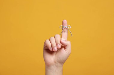 Turuncu arka planda bağlı yay ile işaret parmağı gösteren adam, yakın plan