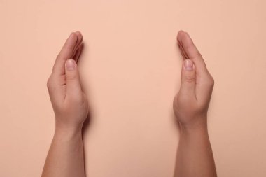 Soluk pembe arka planı olan bir kadın, elleri yakın çekim. Metin için boşluk