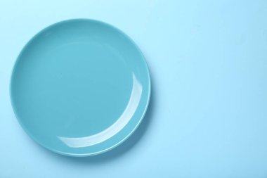 Açık mavi zemin üzerinde boş seramik plaka, üst manzara. Metin için boşluk