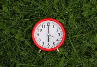 Yeşil çimlerin üzerindeki kırmızı alarm saati, en üst manzara.