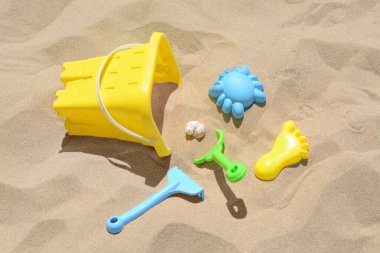 Parlak plastik kova, kumda tırmık ve kürek. Plaj oyuncakları