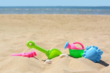 Parlak plastik tırmık ve kürek deniz kenarında kumda. Plaj oyuncakları. Metin için boşluk