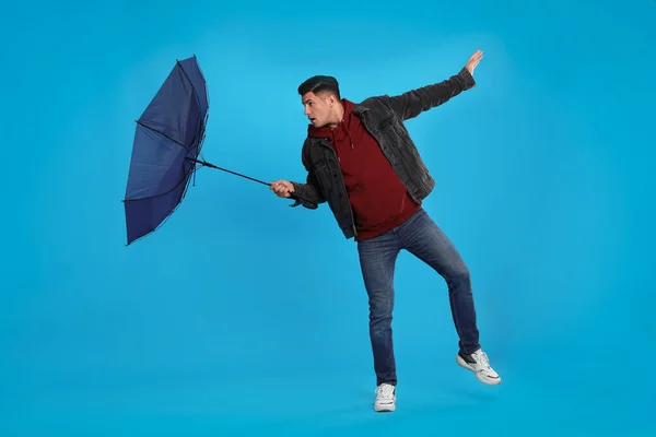 Şemsiyeli Adam Açık Mavi Arka Planda Rüzgarın Esintisine Yakalandı — Stok fotoğraf