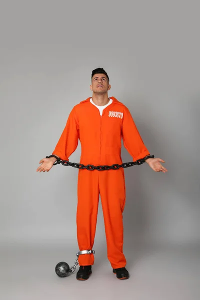 鎖手とグレーの背景に金属ボールとオレンジジャンプスーツの囚人 — ストック写真
