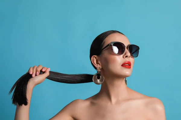 Vonzó Divatos Napszemüveg Megérinti Haját Ellen Világoskék Háttér — Stock Fotó