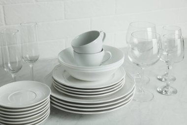 Tezgahta farklı temiz tabak, bardak ve bardaklar var.