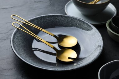 Set of clean tableware on black table, closeup