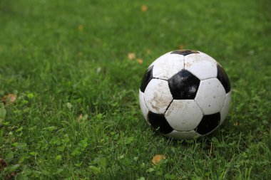 Açık havada yeşil çimlerde kirli futbol topu, metin için alan