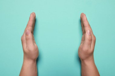 Turkuvaz arka planda tutulan bir kadın, ellerin yakın çekimi. Metin için boşluk