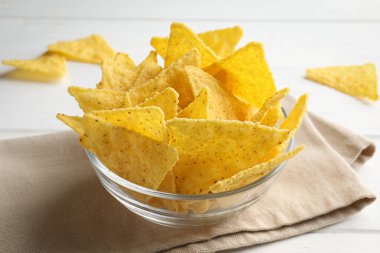 Tortilla chips (nachos) in bowl on white wooden table, closeup